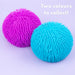 Two textured, spiky squeeze balls in bright magenta pink and cyan blue on a light lavender background, with the text 'Two colours to collect!' in the top right corner.