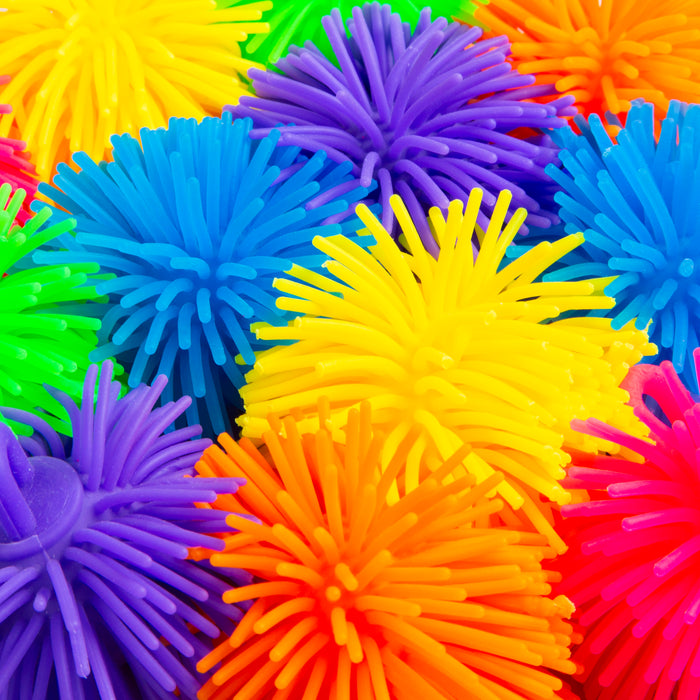 A close-up pile of brightly colored spiky foam balls in yellow, blue, purple, orange, pink, and green.