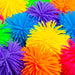 A close-up pile of brightly colored spiky foam balls in yellow, blue, purple, orange, pink, and green.
