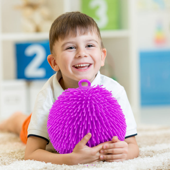 Child holding a purple textured ball in a classroom setting