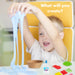 A young boy with blond hair sits in a yellow chair, smiling as he stretches light blue slime with both hands. A white text overlay reads 'What will you create?'.