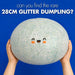 A person holds a very large glittery squishy dumpling toy against a bright blue background, with text at the top reading 'can you find the rare 28CM GLITTER DUMPLING?'.