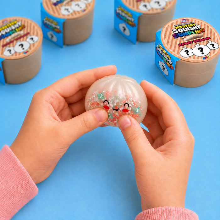 A person's hands holding a clear, bubble-shaped squishy toy filled with multicolor glitter and a cute face, with several colorful 'Squishy World' mystery rolls in the background on a blue surface.
