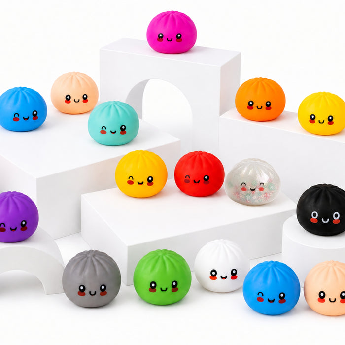 A collection of colourful, cute dumpling-shaped stress balls with smiling faces, displayed on white geometric risers against a white background.