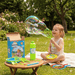 Child playing with bubble wand in a garden with bubble solution and giant bubble kit. 